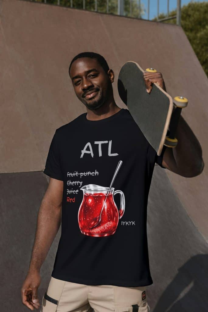Man holding skateboard at skatepark wearing Cousins Dozens skateboarder T-shirt.