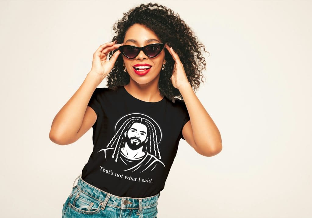 Trendy woman wearing sunglasses and a graphic T-shirt with a beard illustration, smiling confidently.