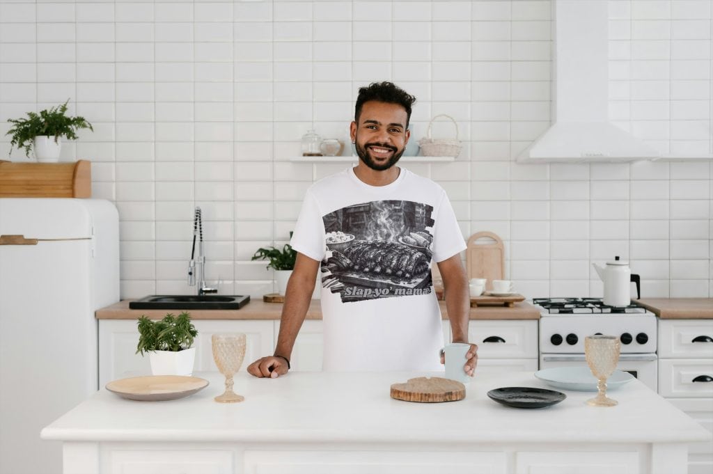 Man preparing a fresh homemade meal in a bright, modern kitchen with white tiles and minimal decor.