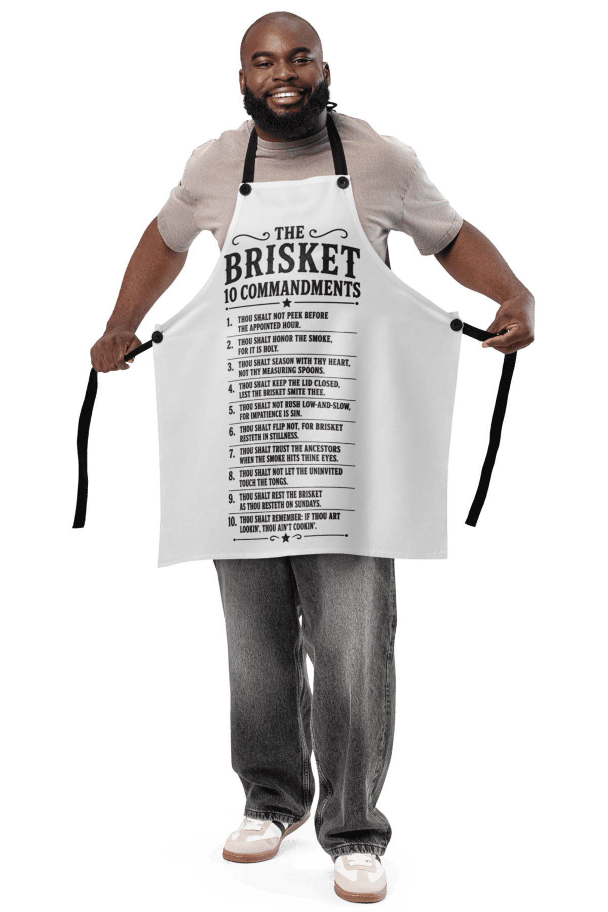 Man wearing a "Brisket" apron with commandments printed on it, smiling and holding the apron open.