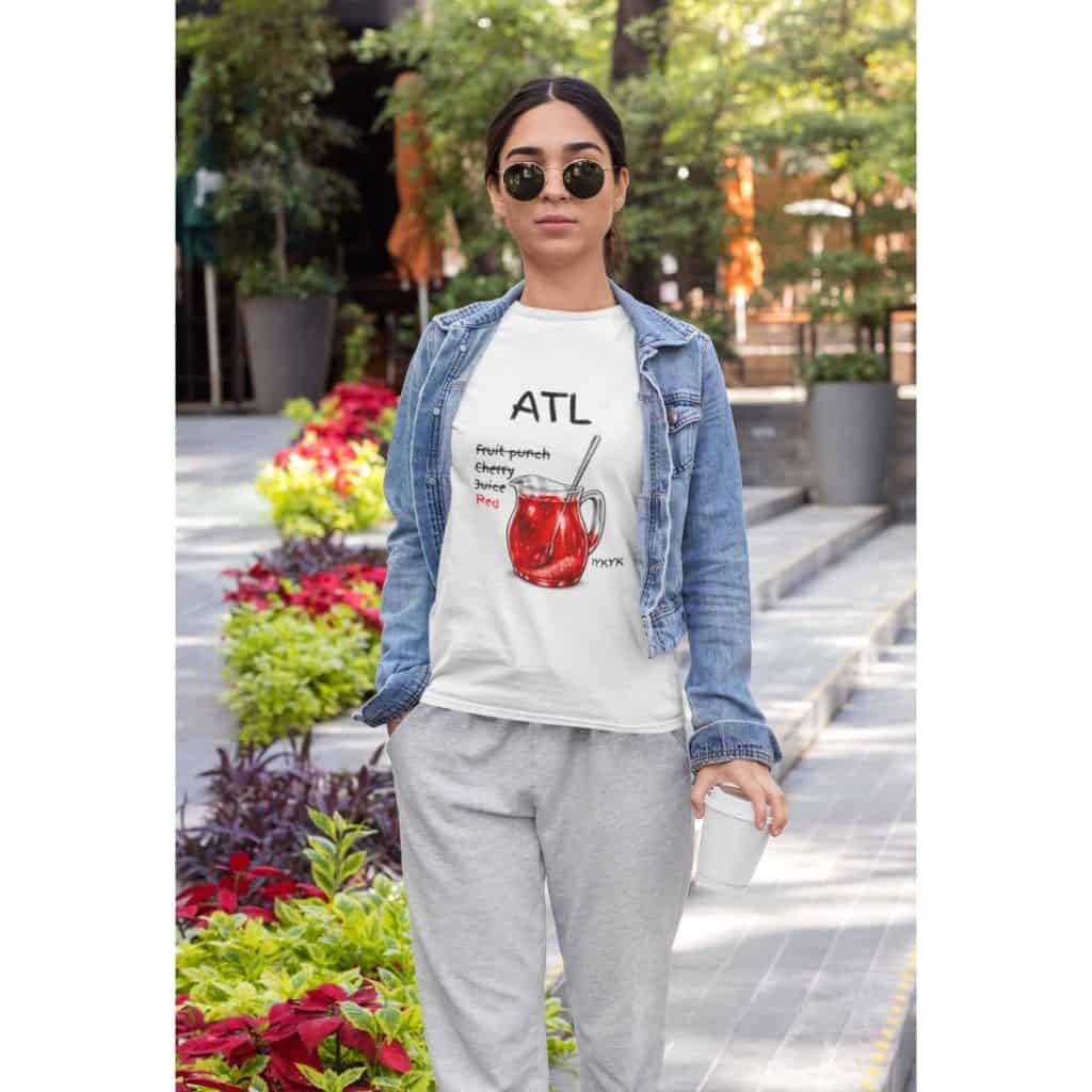 Woman wearing casual outfit with sunglasses in city park, holding coffee, surrounded by greenery and.