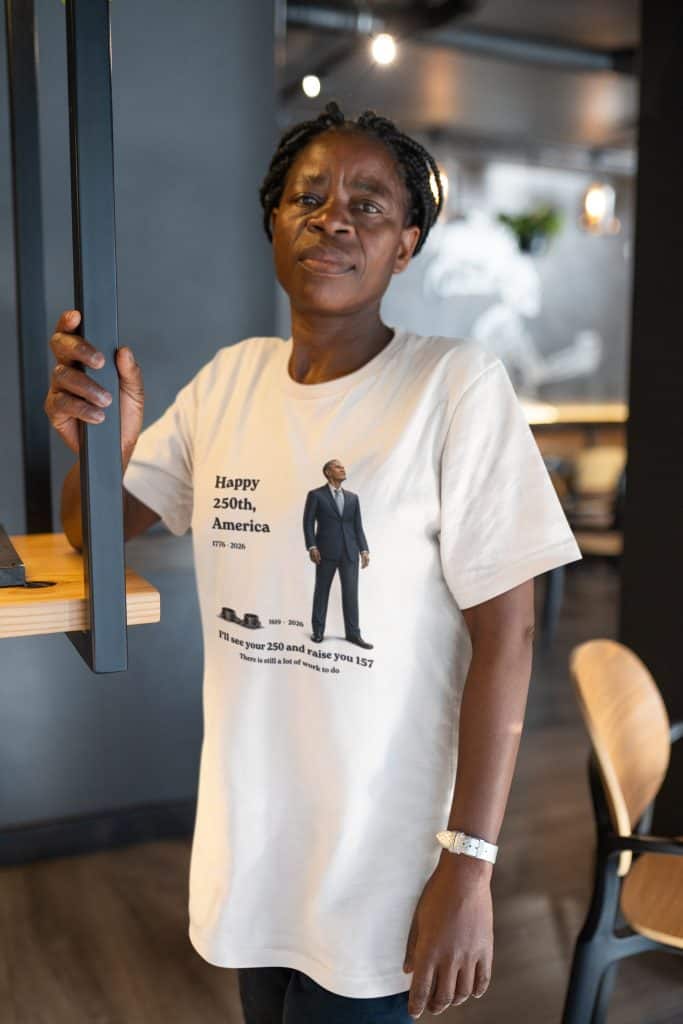 Woman wearing a T-shirt celebrating America's 250th anniversary in a modern cafe.