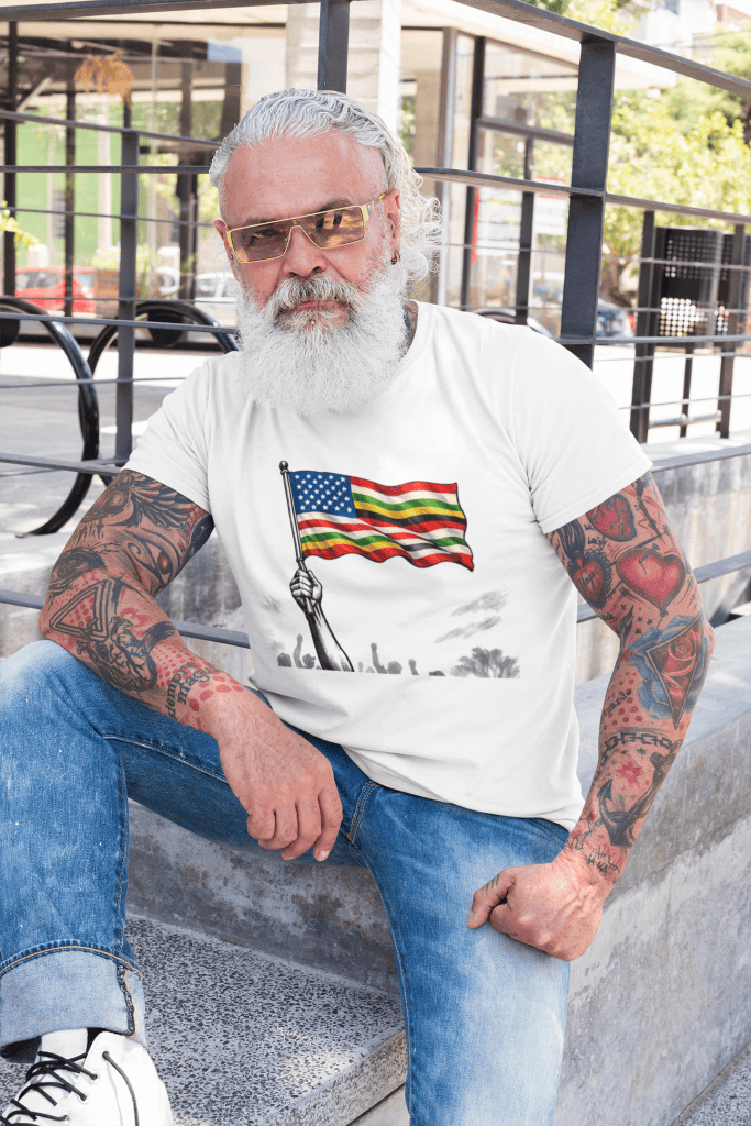 American flag t-shirt worn by tattooed man with white beard and sunglasses outdoors.