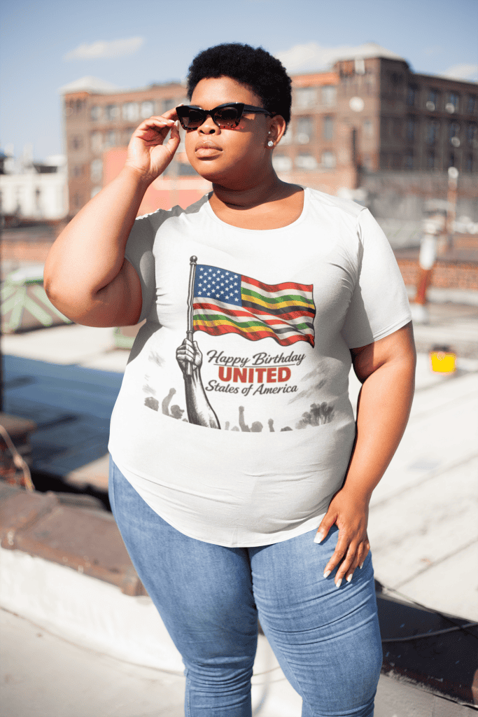 Woman with sunglasses wearing a "Happy Birthday United States of America" T-shirt outdoors.