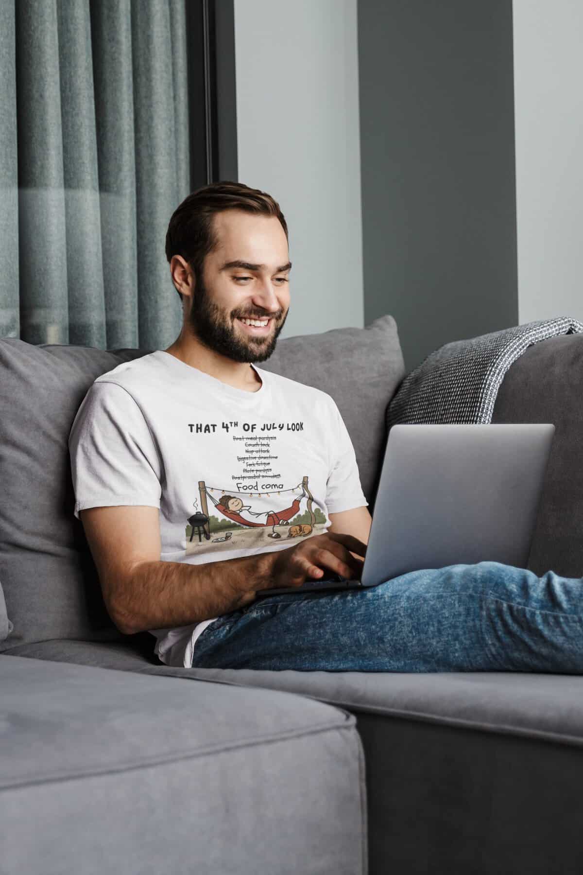 Happy man working on laptop while sitting on sofa in living room.