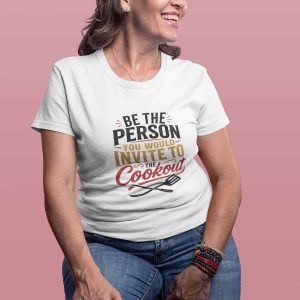 Smiling woman in casual outfit with "Be the Person You Invite to Cookout" t-shirt.